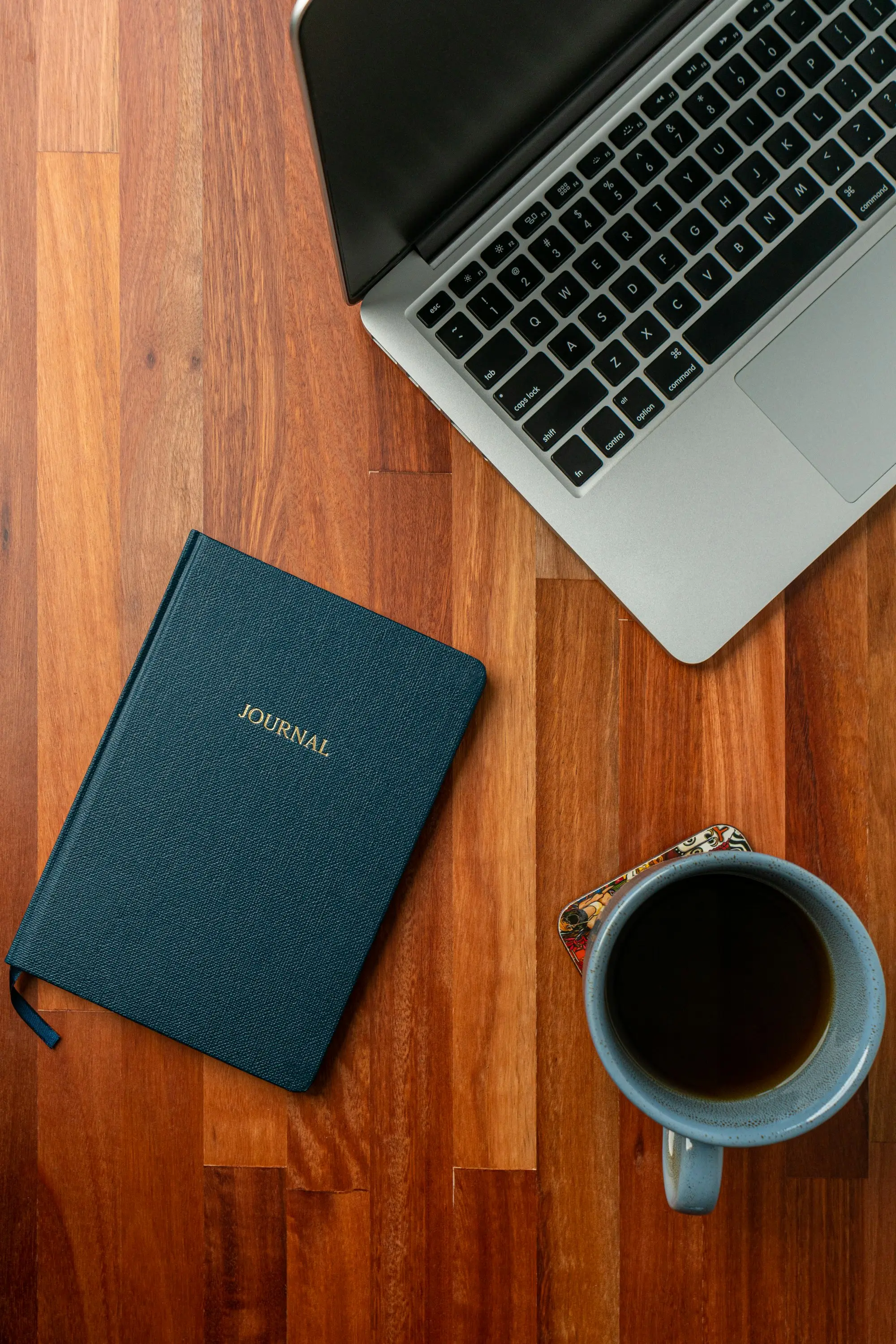 Carnet, tasse de café et ordinateur portable sur un bureau en bois